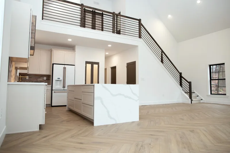 Open kitchen with a waterfall island, wood floor and staircase to a loft