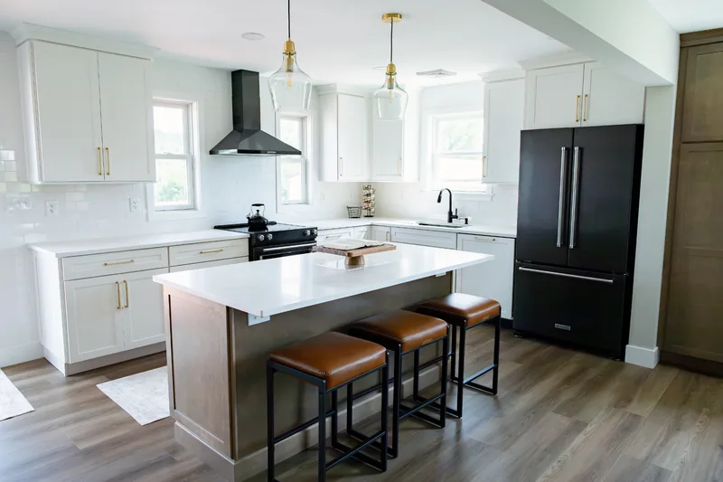 Kitchen with white cabinets, black appliances, a wood island and stools